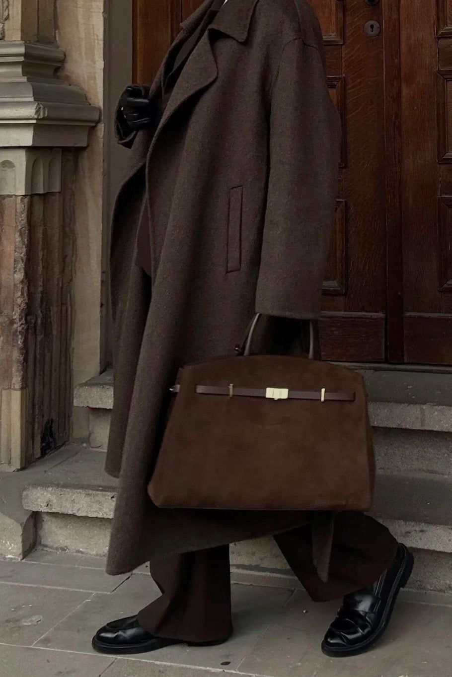 Brązowy rozkloszowany płaszcz z paskiem w stylizacji z czekoladowym eleganckim komplecie garniturowym - widok z boku