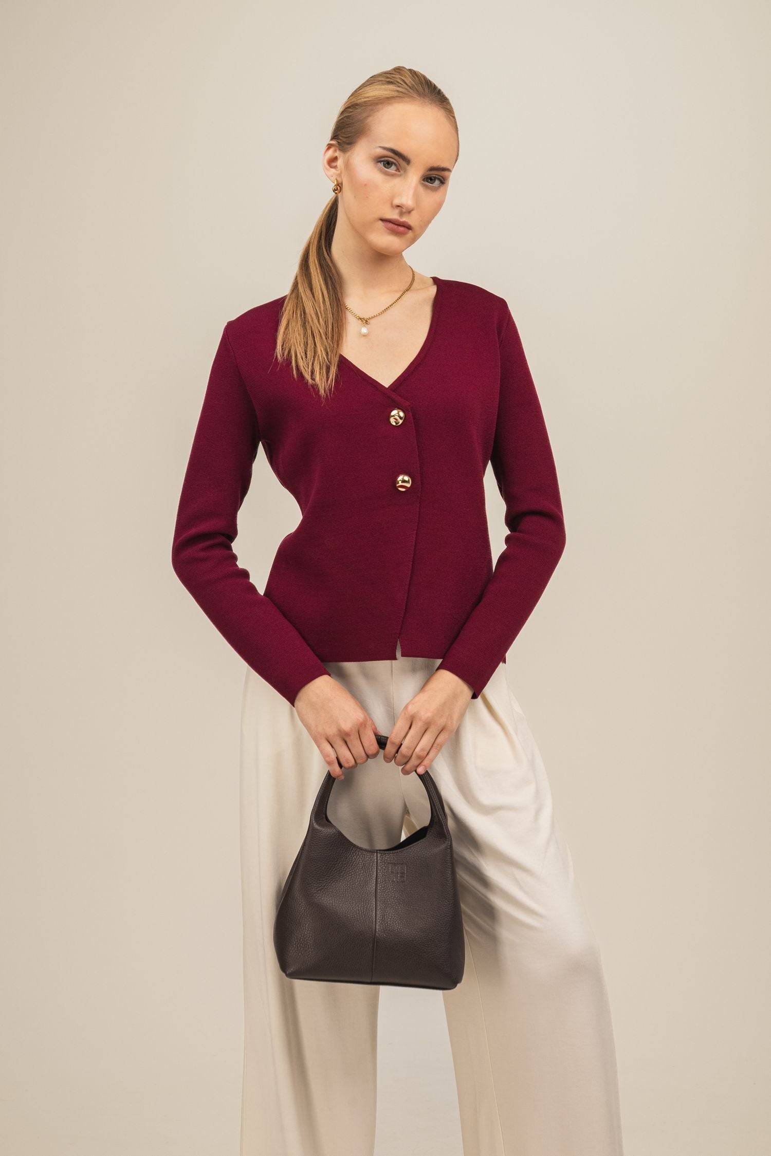 Sweter Amara – elegancki kardigan damski w kolorze bordo wystylizowany z białymi spodniamii brązową skórzaną torebką do ręki