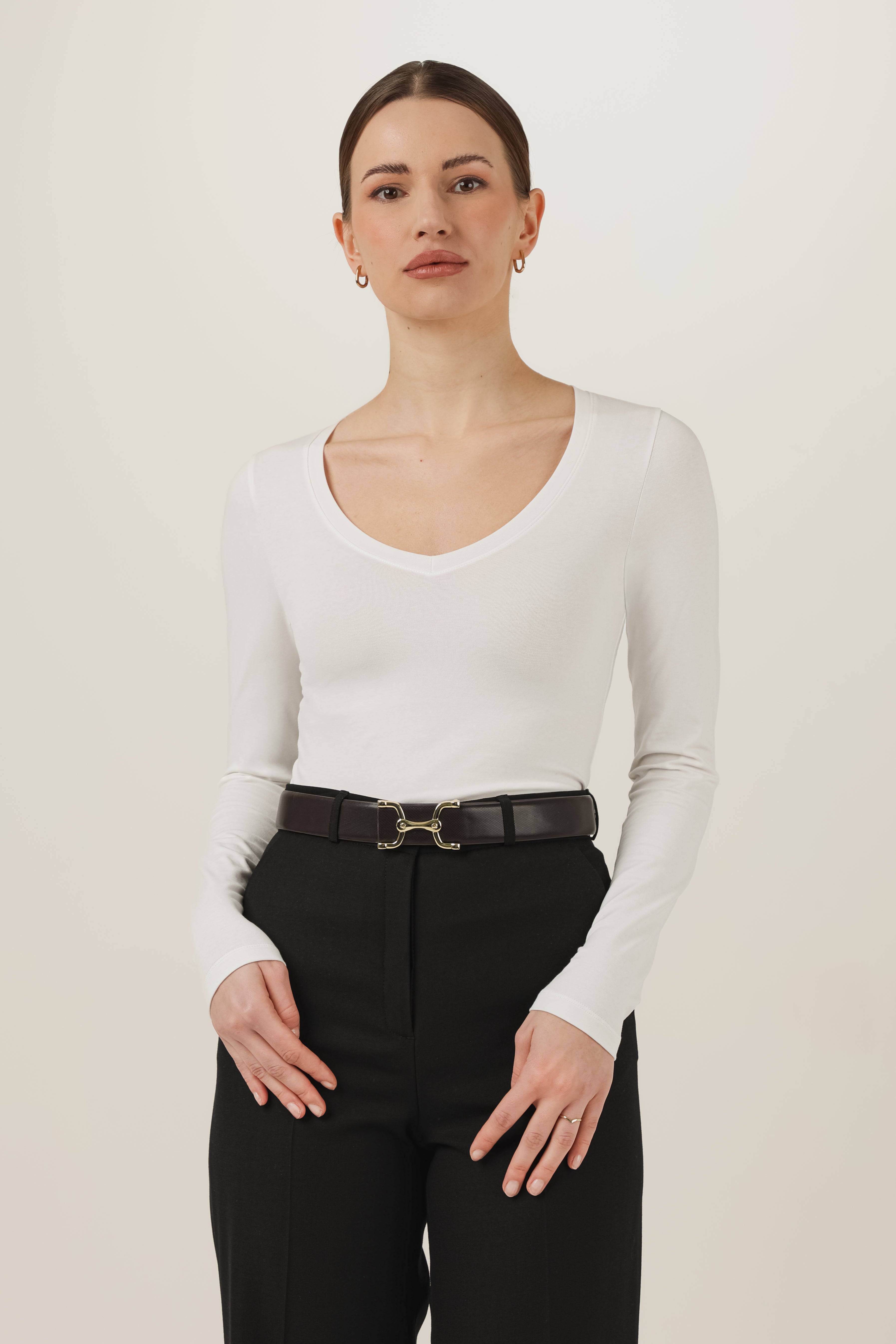 Dopasowany biały top z długim rękawem i dekoltem V z czarnymi spodniami z wysokim stanem - zbliżenie na top