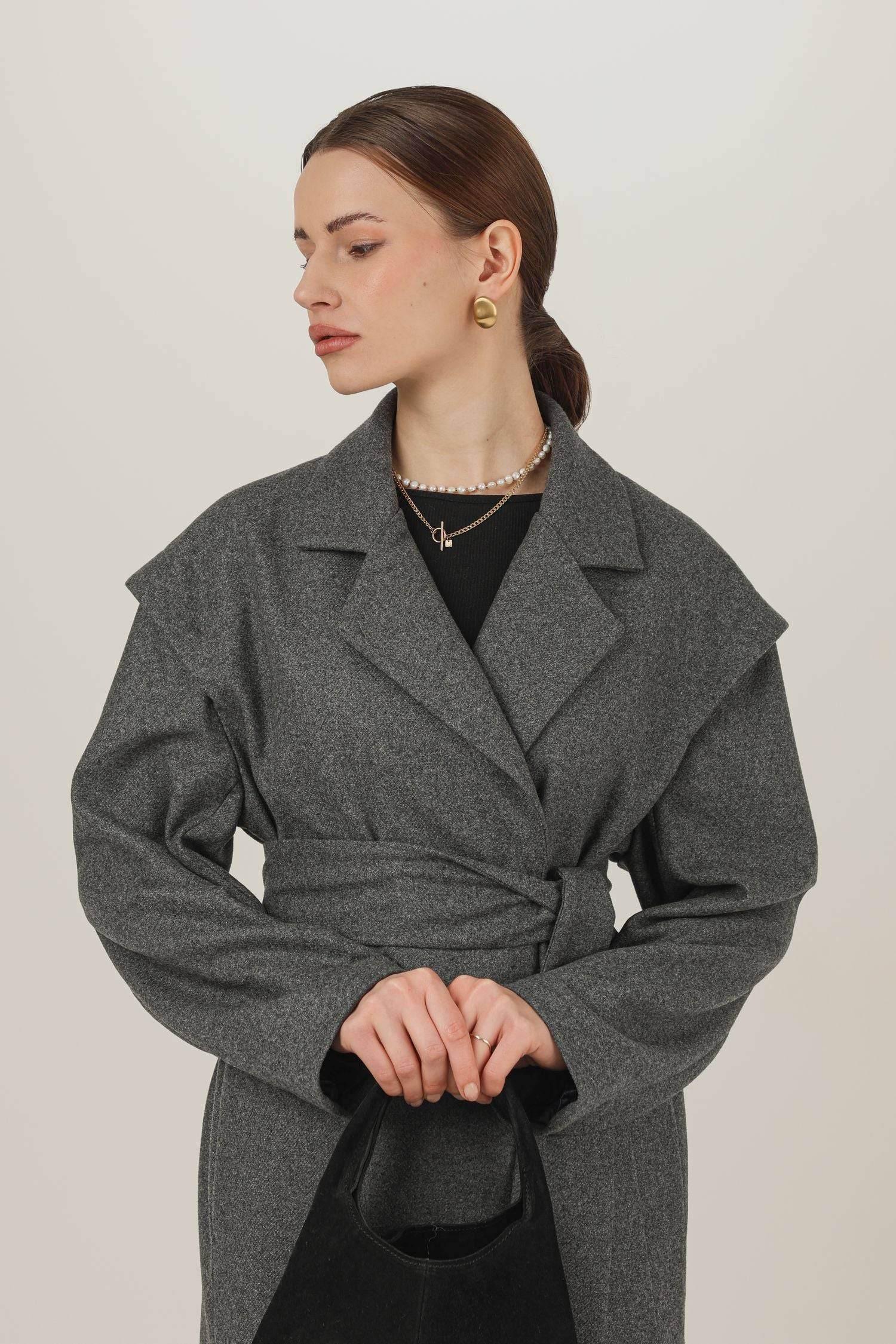 Szary płaszcz z wełny i kaszmiru z szerokimi ramionami związany w tali paskiem - przybliżenie na dekolat