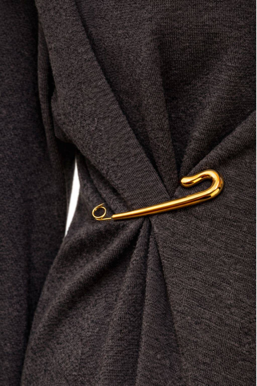 Agrafka wykonana ze stali szlachetnej w złotym kolorze przypięta i modeluję klasyczną czarną marynarkę oversize, nadając stylizacji kształtów i elegancji