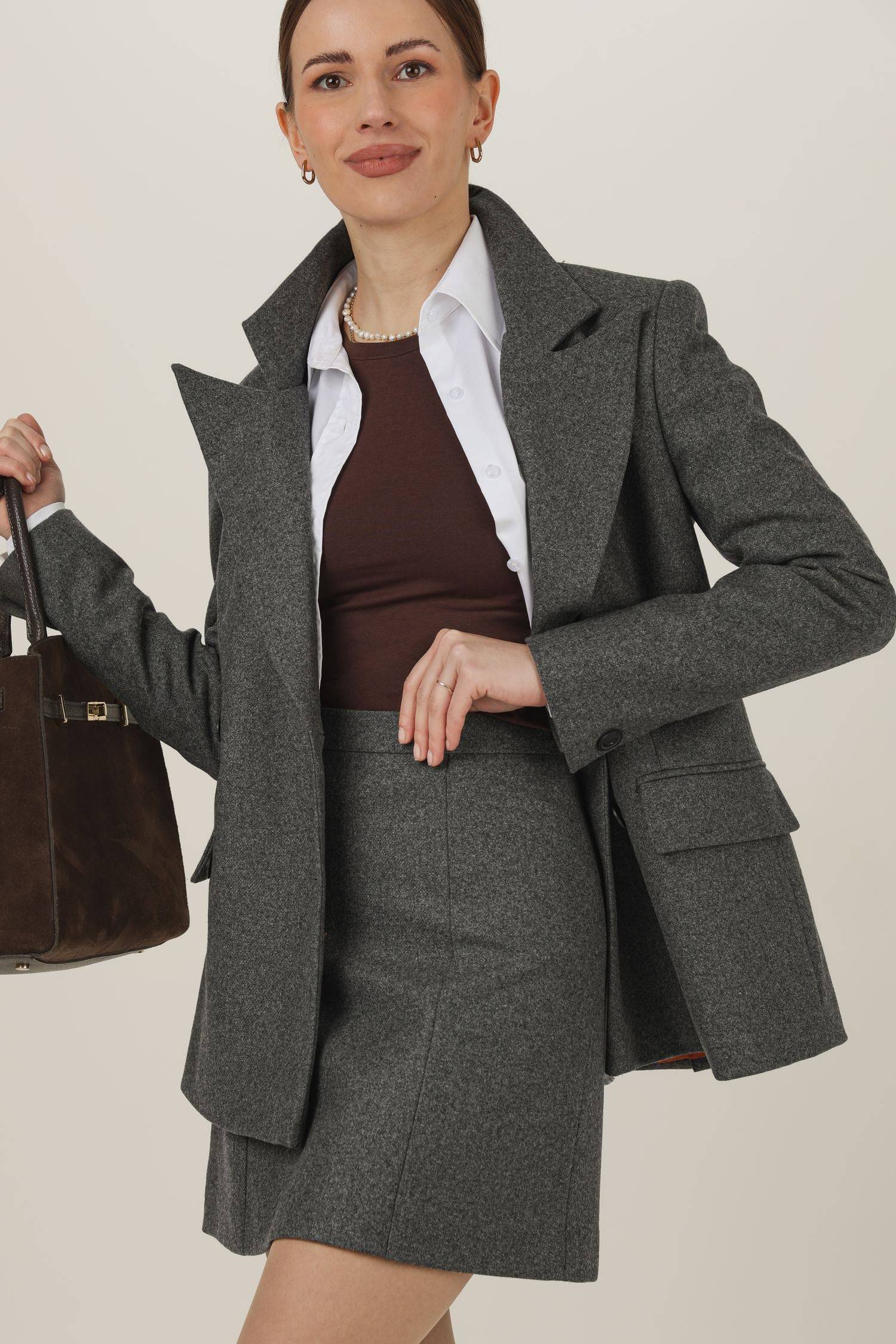 Szara wełniana spódnica z kaszmirem Eliot w połączeniu z szarą marynarką Eliot, białą rozpiętą koszulą i czekoladowym topem