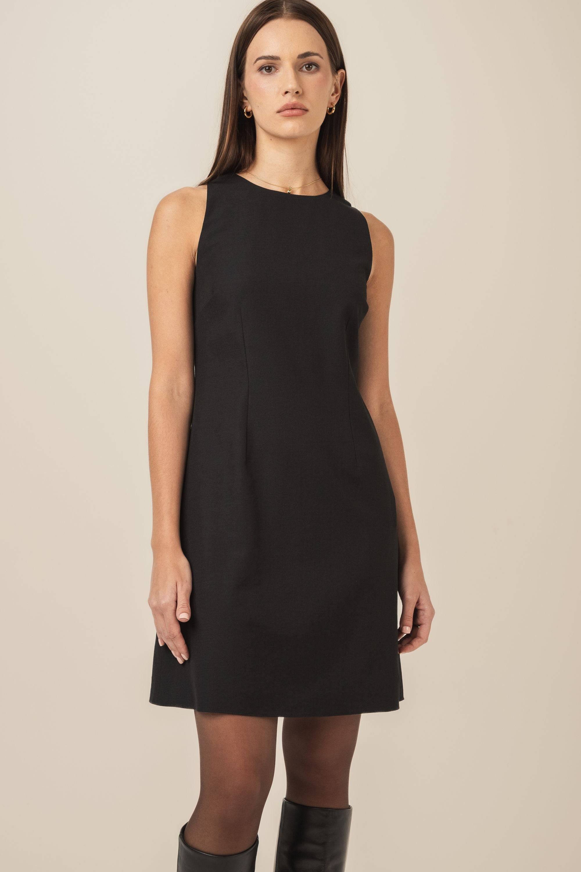 Elegancka mała czarna sukienka trapezowa z wysokimi skórzanymi kozakami - zbliżenie na sukienkę