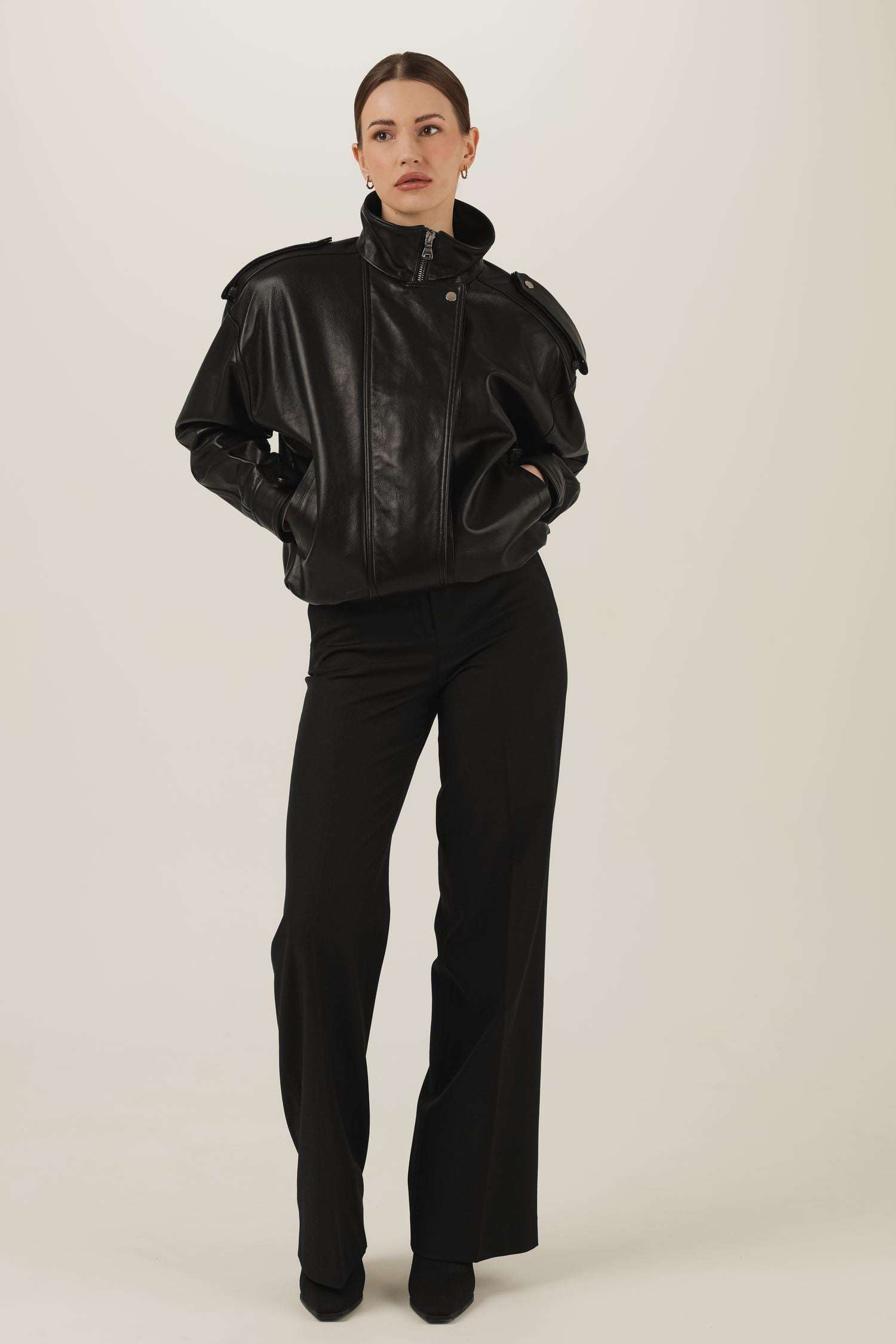 Czarna skórzana kurtka w stylu lat 90. oversize zapięta z czarnymi eleganckimi spodniami z prostą nogawką 