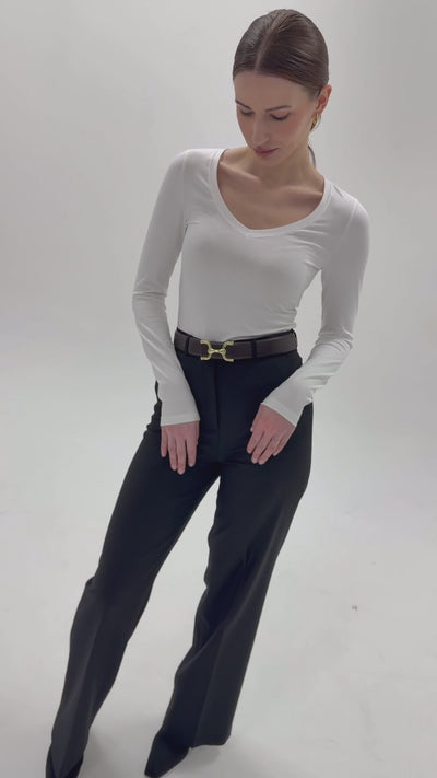 Dopasowany biały top z długim rękawem i dekoltem V z czarnymi spodniami z wysokim stanem - cała stylizacja
